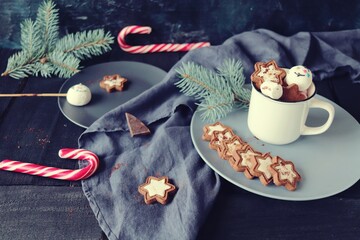 Christmas, New Year, a cup of coffee with meringues and marshmallows, caramel candies, a plate of cookies on a linen cloth on a dark wooden table, a festive atmosphere, a rustic retro style