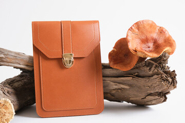 brown bag and mushrooms on driftwood, gray background, eco leather from mushroom mycelium