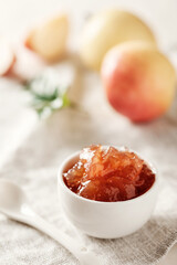 Apple jam in a small bowl. Apple jam on a light background. Delicious natural marmalade.