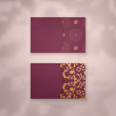 Business card template in burgundy color with luxurious gold pattern for your contacts.