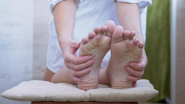 Hands of a Masseur, Therapist are Massaging Bare Feet, Soles of a Child. Pressing acupuncture points of foot with fingers. Reflex massage. Effective treatment, improves blood circulation in soles. 4K.