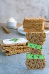Diet concept. Rye bread, wholesome and tasty, crisp appetizer, grabbed by a tape measure, Crispbread.
