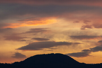 Cloudy sky at sunset over the hill.