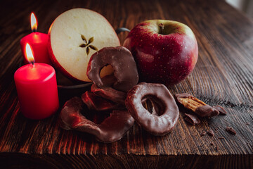 Apple rings with chocolate glaze. Still life with winter apple and red candles on rustic wood. Background for winter and christmas time.