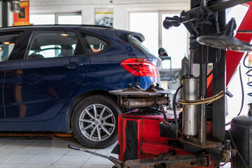 Photo of a blue passenger car at the service station. Machine for tire fitting of auto wheels