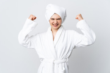 Teenager girl in a bathrobe isolated on white background celebrating a victory