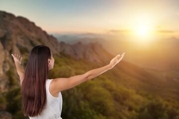 Fototapeta na wymiar Woman raised hands up on top of mountain and sunset background. Freedom, Pray,