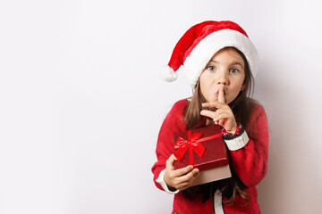 Happy child girl in Christmas hat holding red gift box isolated on white background