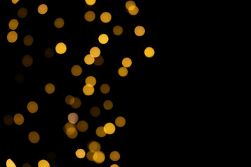 Bokeh golden lights background. Blurred Christmas garland lights on left side on a black background