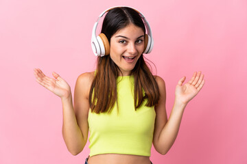 Fototapeta premium Young caucasian woman isolated on pink background surprised and listening music