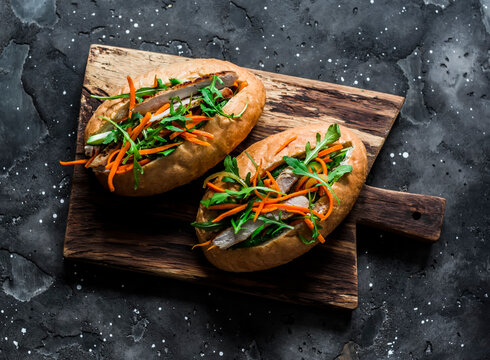 Pork Banh Mi hot dogs with spicy carrot on cutting board on a dark background, top view. Delicious snack, tapas