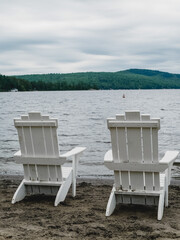 two wooden adirondack chairs on the beach