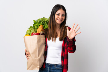 Young caucasian with vegetables isolated on white background counting five with fingers