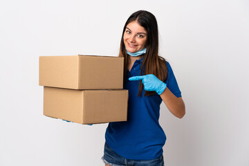 Young delivery woman protecting from the coronavirus with a mask isolated on white background and pointing it