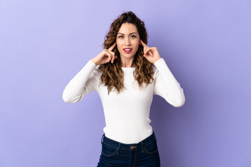 Young caucasian woman isolated on purple background frustrated and covering ears