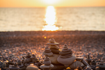 Stones pyramid on pebble symbolizing zen, harmony, balance. Ocean at sunset in the background