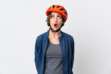Young cyclist woman isolated on white background looking up and with surprised expression