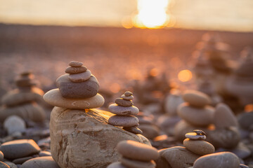 Stones pyramid on pebble symbolizing zen, harmony, balance. Ocean at sunset in the background