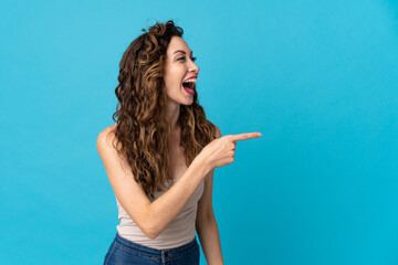 Obraz premium Young caucasian woman isolated on blue background pointing finger to the side and presenting a product