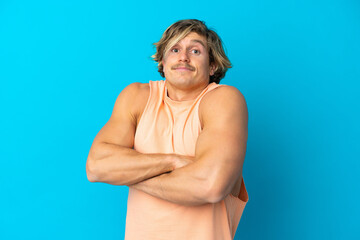 Handsome blonde man isolated on blue background making doubts gesture while lifting the shoulders