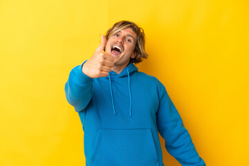 Handsome blonde man isolated on yellow background with thumbs up because something good has happened