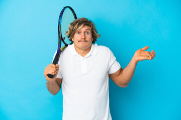 blonde tennis player man isolated on blue background having doubts while raising hands