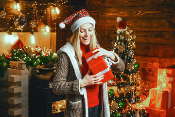 Woman open christmas gift near christmas tree. Girl enjoy cozy atmosphere christmas eve or noel.