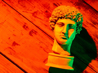 Gypsum copy of ancient statue Hermes head in orange green neon light. Neon image with ancient greek...