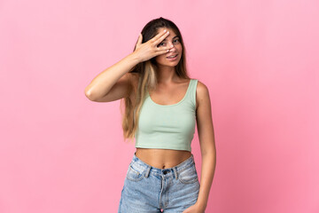 Young caucasian woman isolated on pink background covering eyes by hands and smiling