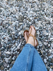 bare feet in leather sandals among small stones