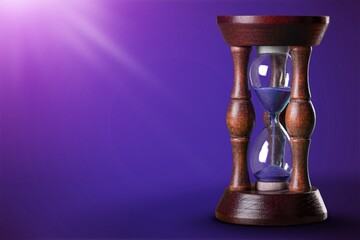 An hourglass with little time left sand on the desk.