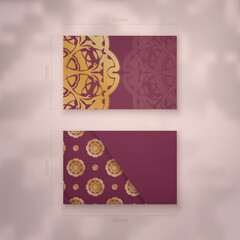 Presentable business card in burgundy color with Indian gold ornaments for your business.