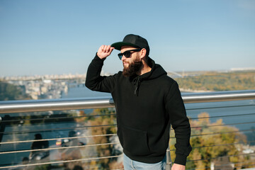City portrait of handsome hipster guy wearing black blank hoodie with space for your logo or...
