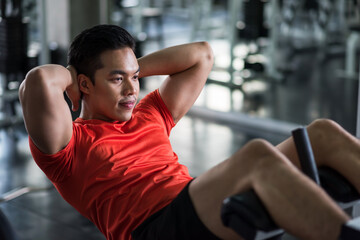 Asian muscular young man sit-ups in gym
