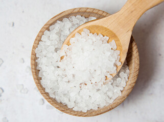 Large white sea salt in a wooden spoon on a concrete background close up
