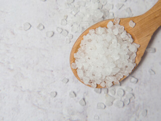 Large white sea salt in a wooden spoon on a concrete background close up