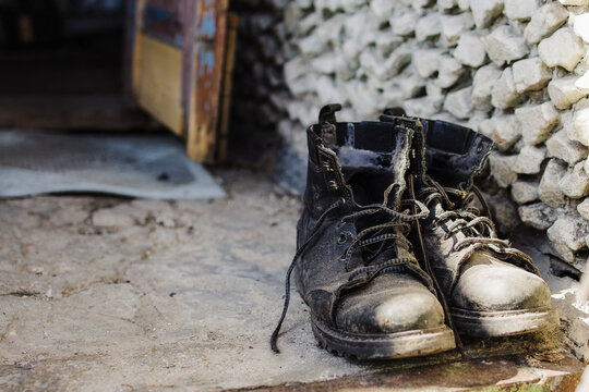 old dirty frayed mens military-motorcycle boots stand on the doorstep