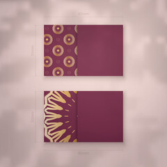 Visiting business card in burgundy color with mandala gold pattern for your business.