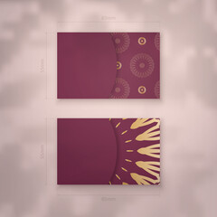 Visiting business card in burgundy color with mandala gold pattern for your contacts.
