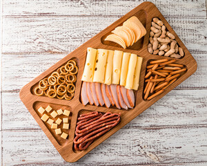 Antipasto cold meat dish with breadsticks, prosciutto, ham, ham slices and cheese on a wooden tray