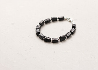 Black tourmaline, sherl bracelet. Bracelet made of stones on hand from natural stone Black tourmaline, sherl on light concrete modern background. Magic jewelry, lithotherapy and stone therapy