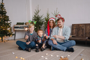 Happy traditional modern family greets Christmas. Light sparklers together for the holiday. New...