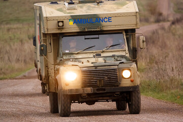 with obscured faces an army ambulance drives along a stone track on a military exercise