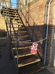 chained off outside metal staircase and a brick wall with strictly no admittance sign