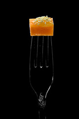 fast food on a fork, appetizer, cheese with honey and sesame seeds, on a black background.