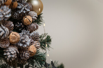 Merry Christmas decorated fir tree branches with painted shiny diy cones, golden garland lights, close up shot, copy space. Place for text