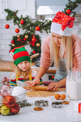 Family of mother and daughter make homemade gingerbread for christmas at decorated kitchen at home. Christmas atmosphere, preparing