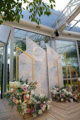 Beautiful decorative photo zone with glass geometry, neon circle and colorful flowers compositions in some café or restaurant interior.