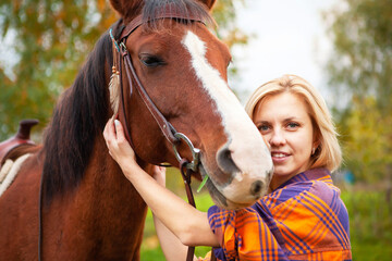 Fototapeta premium Beautiful young blond woman with a horse, portrait.