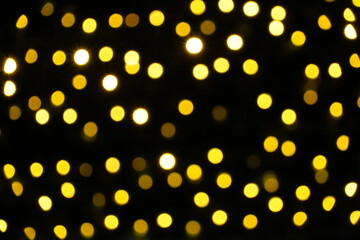 Fototapeta na wymiar Defocuses Christmas lights in yellow shades on a Christmas tree outdoors at night. Suitable as Christmas or seasonal background.